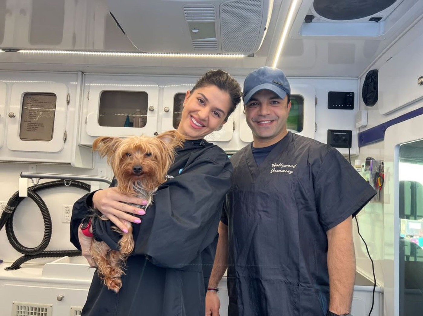Chuck and Yael, founders of Hollywood Rescue Grooming Foundation, inside one of their mobile grooming vans holding a Yorkie